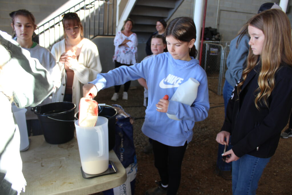 A student scoops powder into a pitcher.