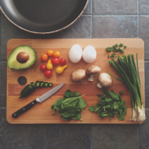 wooden cutting board with knife and vegetables