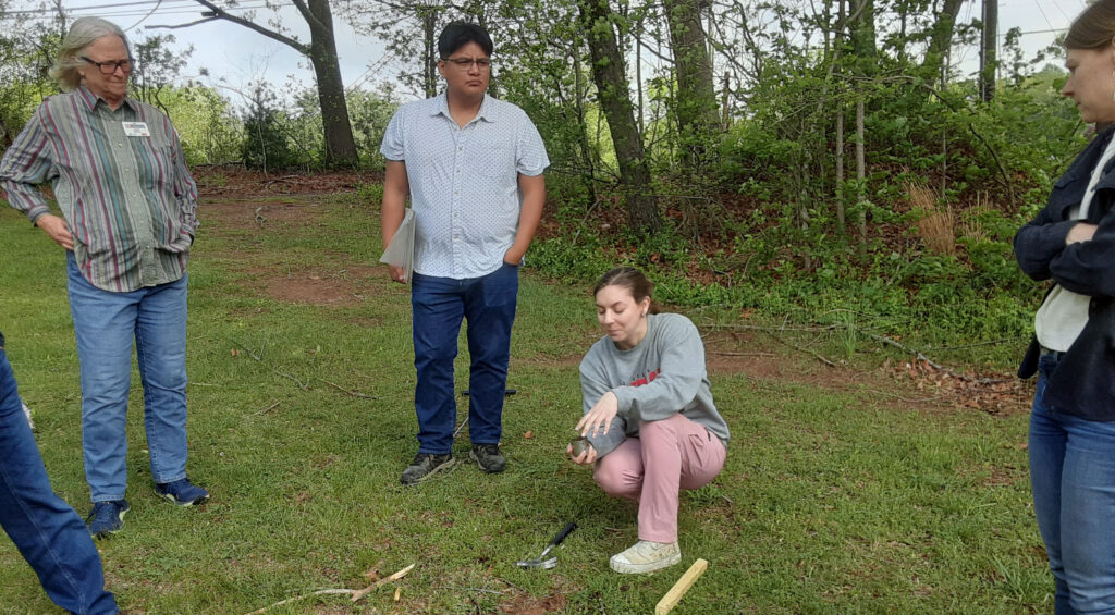 NC State University graduate student Carlee Epting demonstrates tools and techniques on obtaining a soil sample for testing.