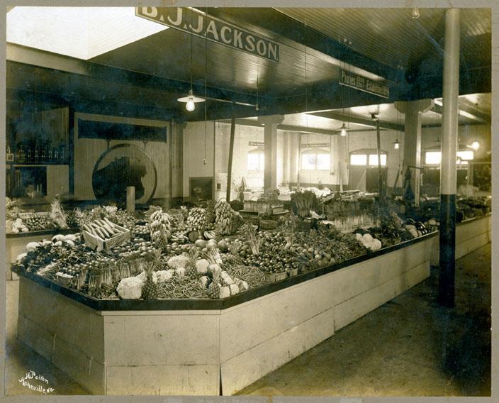 Black and white photo of BJ Jackson's produce market in the City Market of Asheville, NC's City Hall building in the early 1920s.